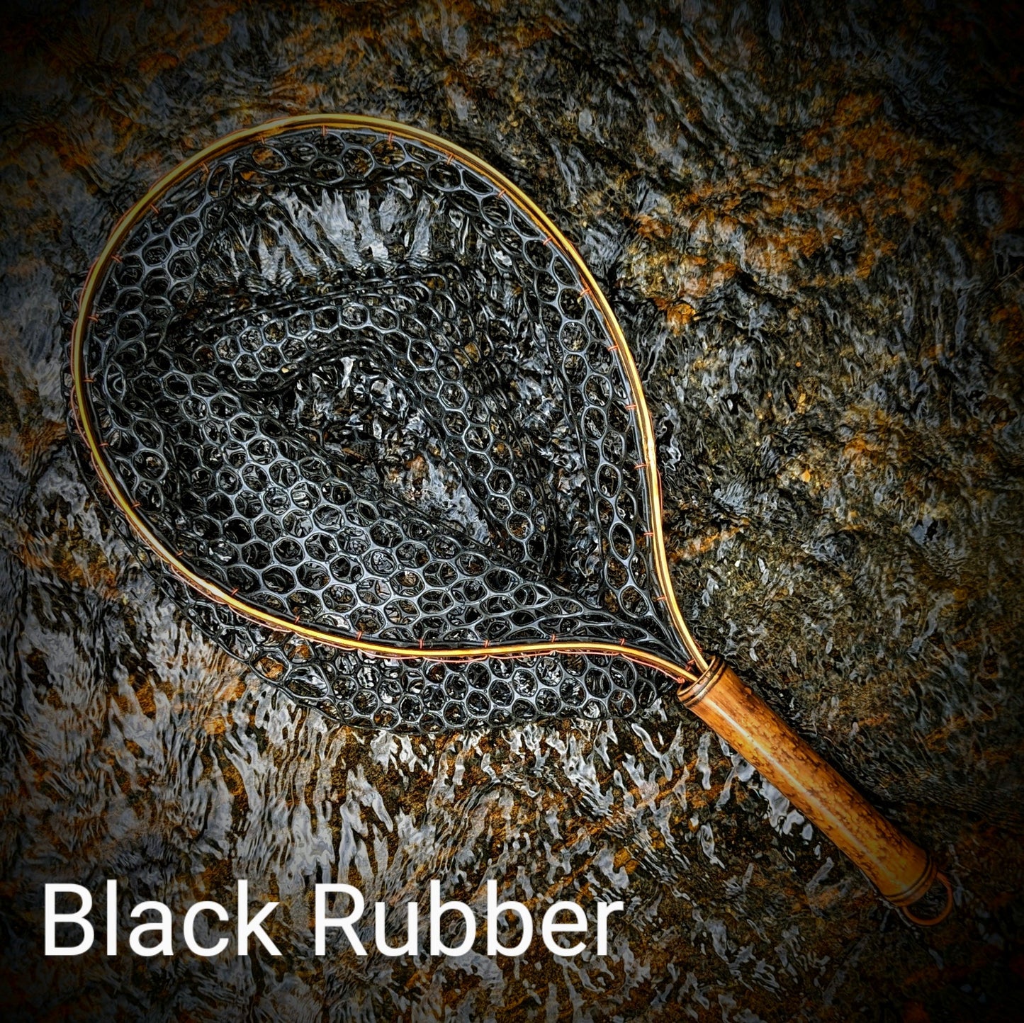 A bamboo fly fishing net lying on a rock in the water on the river in Western North Carolina. The rubber net basket is smooth and shiny and protects the fish for catch and release. The handle is flame cured for strength and durability and there is copper stitching and a copper keeper ring to attach your net keeper to.
