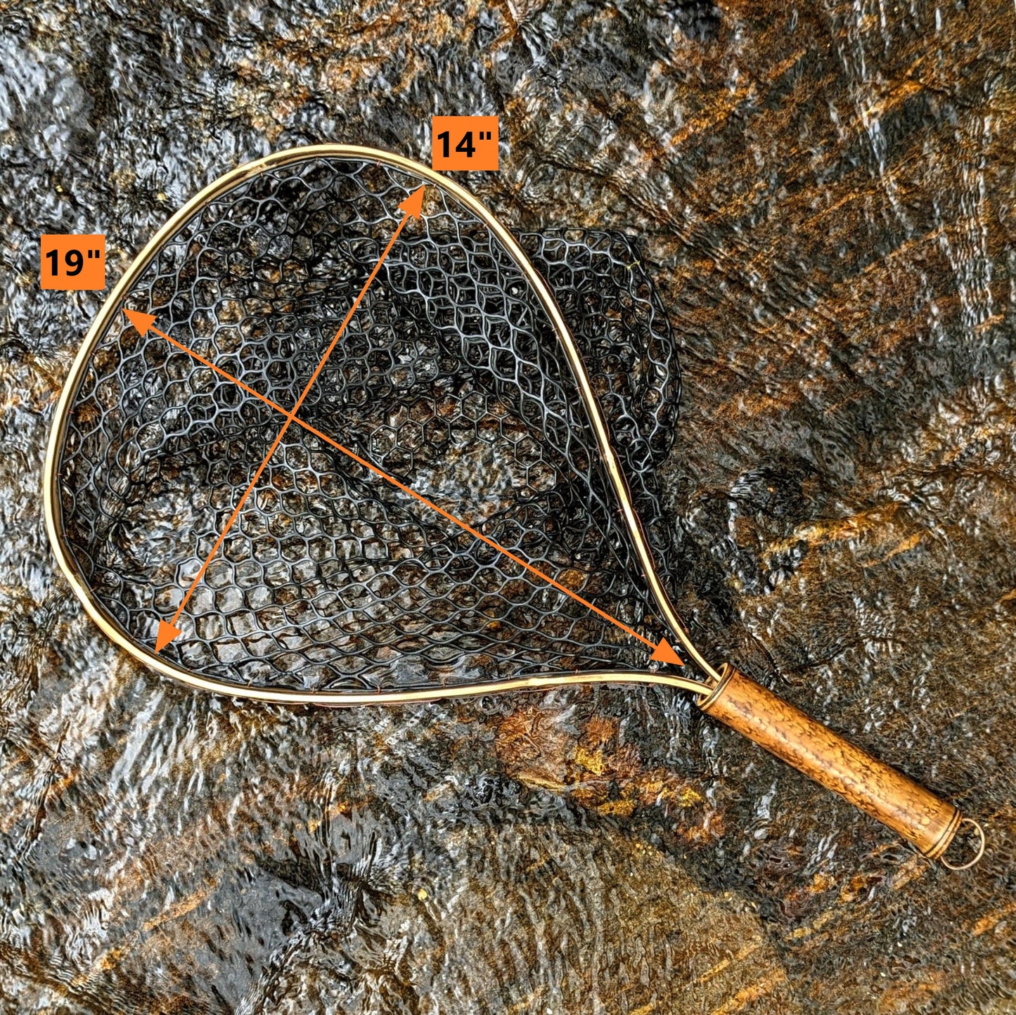 A bamboo fly fishing net lying on a rock in the water on the river in Western North Carolina. The rubber net basket is smooth and shiny and protects the fish for catch and release. The handle is flame cured for strength and durability and there is copper stitching and a copper keeper ring to attach your net keeper to.